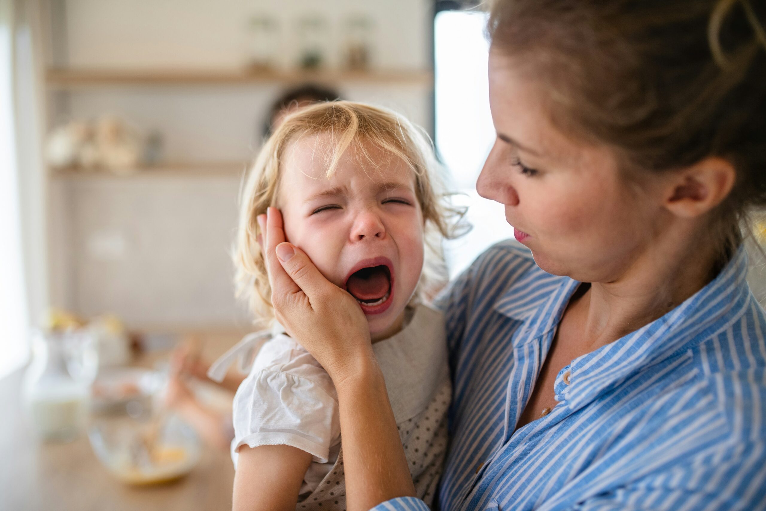 A mother gently holding her child during a tantrum, showing empathy and calm support as the child expresses intense emotions