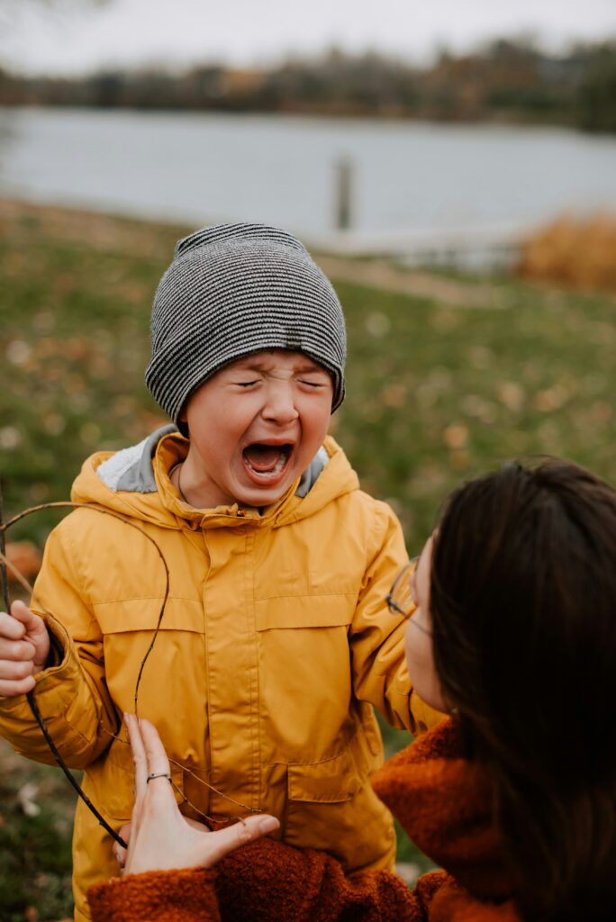 A mother gently holding her child during a tantrum, showing empathy and calm support as the child expresses intense emotions.